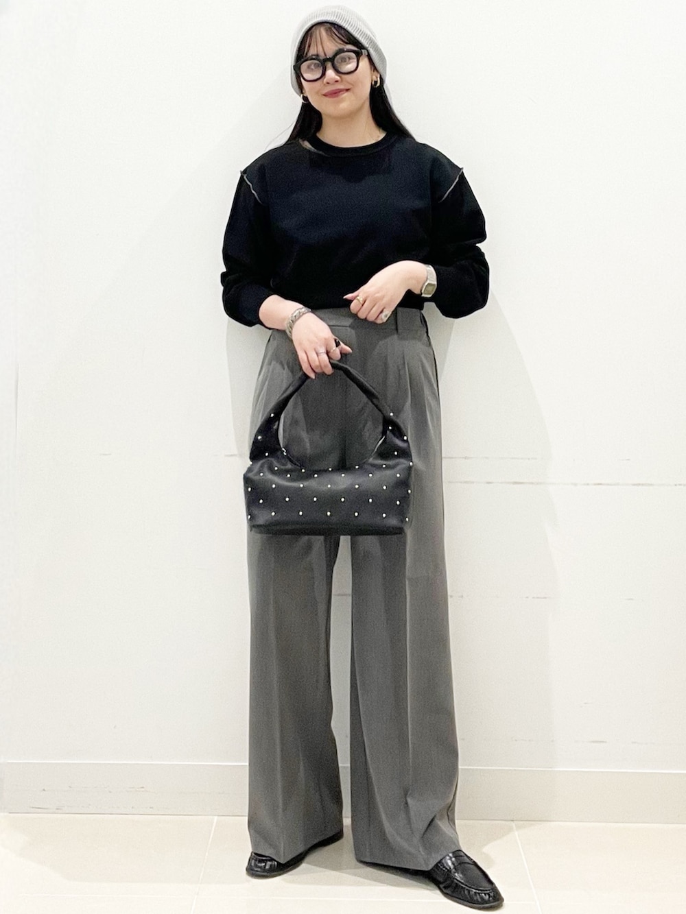 グレー系のスラックス、ブラック系のハンドバッグ、ブラック系のスウェットを着用したレディースの春コーディネートの3枚目の写真
