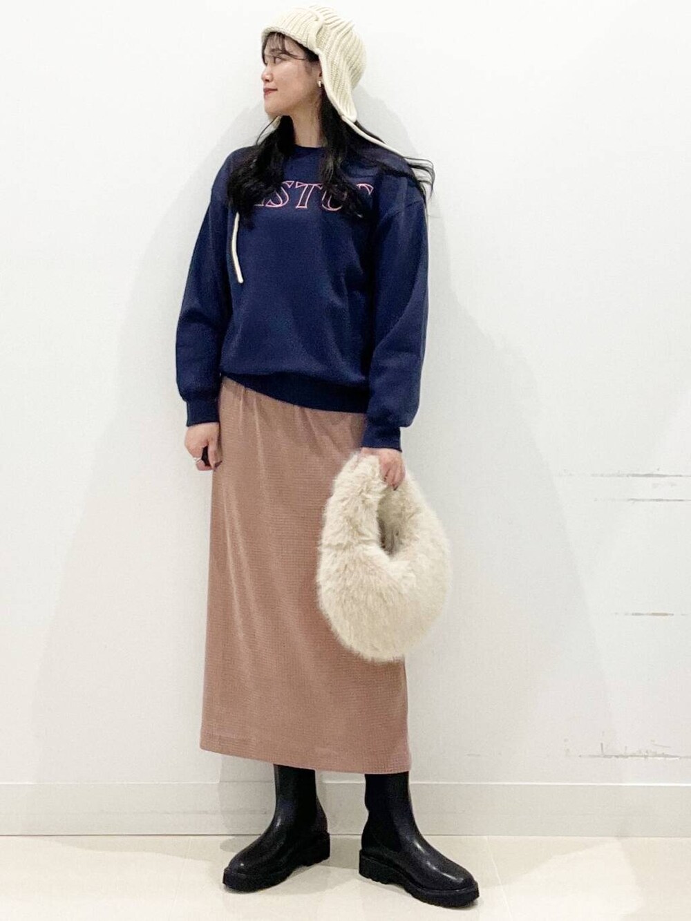 ベージュ系のハンドバッグ、ブラック系のブーツ、ピンク系のスカートを着用したレディースの秋コーディネートの3枚目の写真