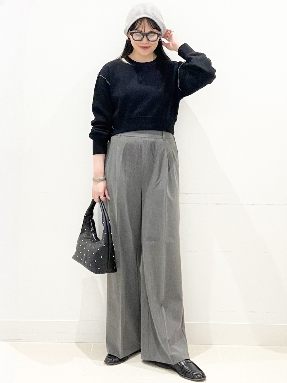 グレー系のスラックス、ブラック系のハンドバッグ、ブラック系のスウェットを着用したレディースの春コーディネートの4枚目の写真