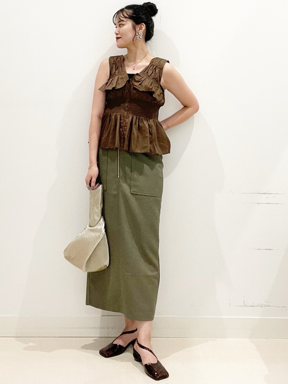 グリーン系のスカート、ブラック系のキャミソール、ゴールド系のハンドバッグを着用したレディースの夏コーディネートの3枚目の写真