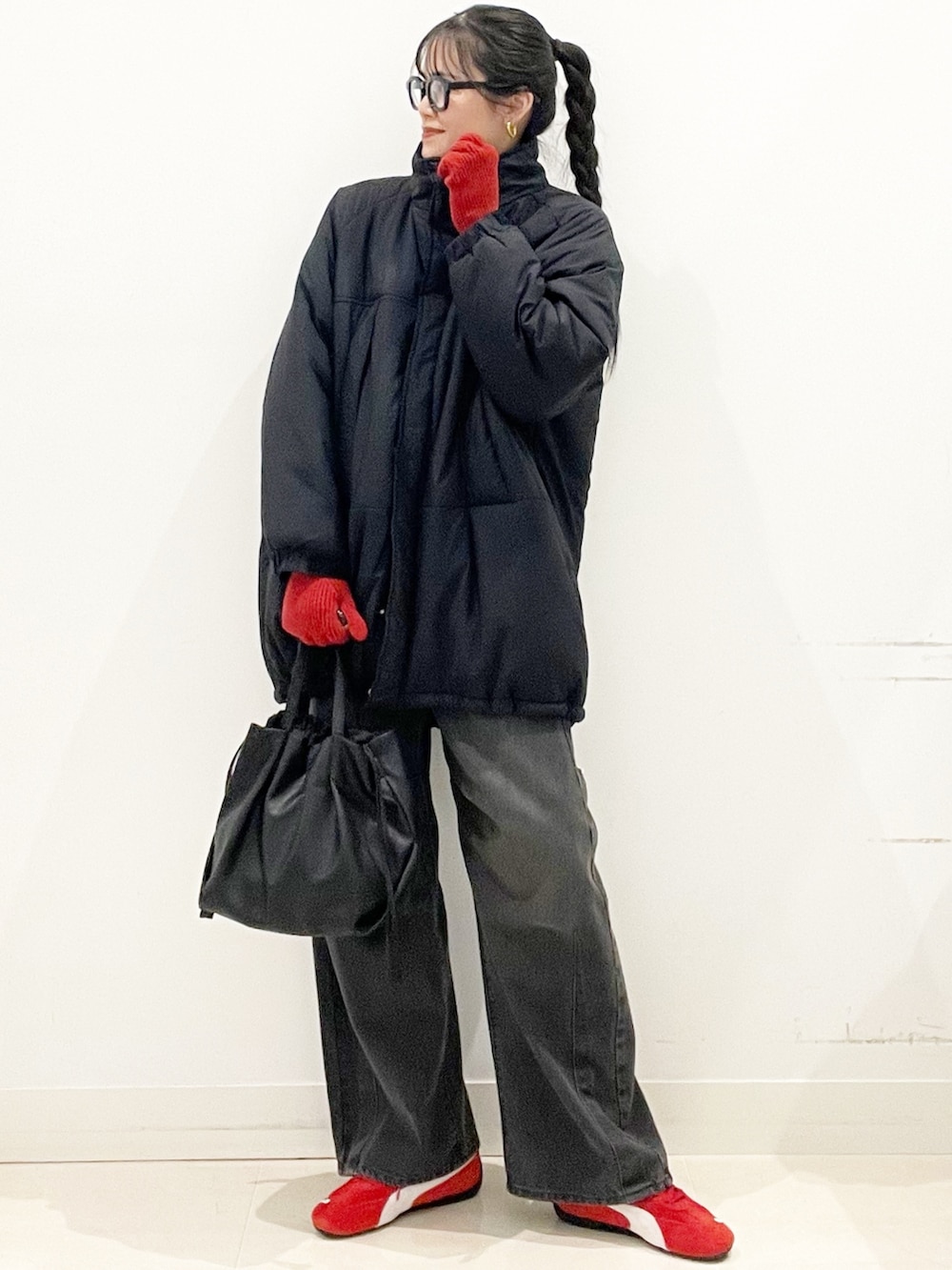 レッド系のスニーカー、ブラック系のダウンジャケット/コート、グレー系のデニムパンツを着用したレディースの冬コーディネートの2枚目の写真