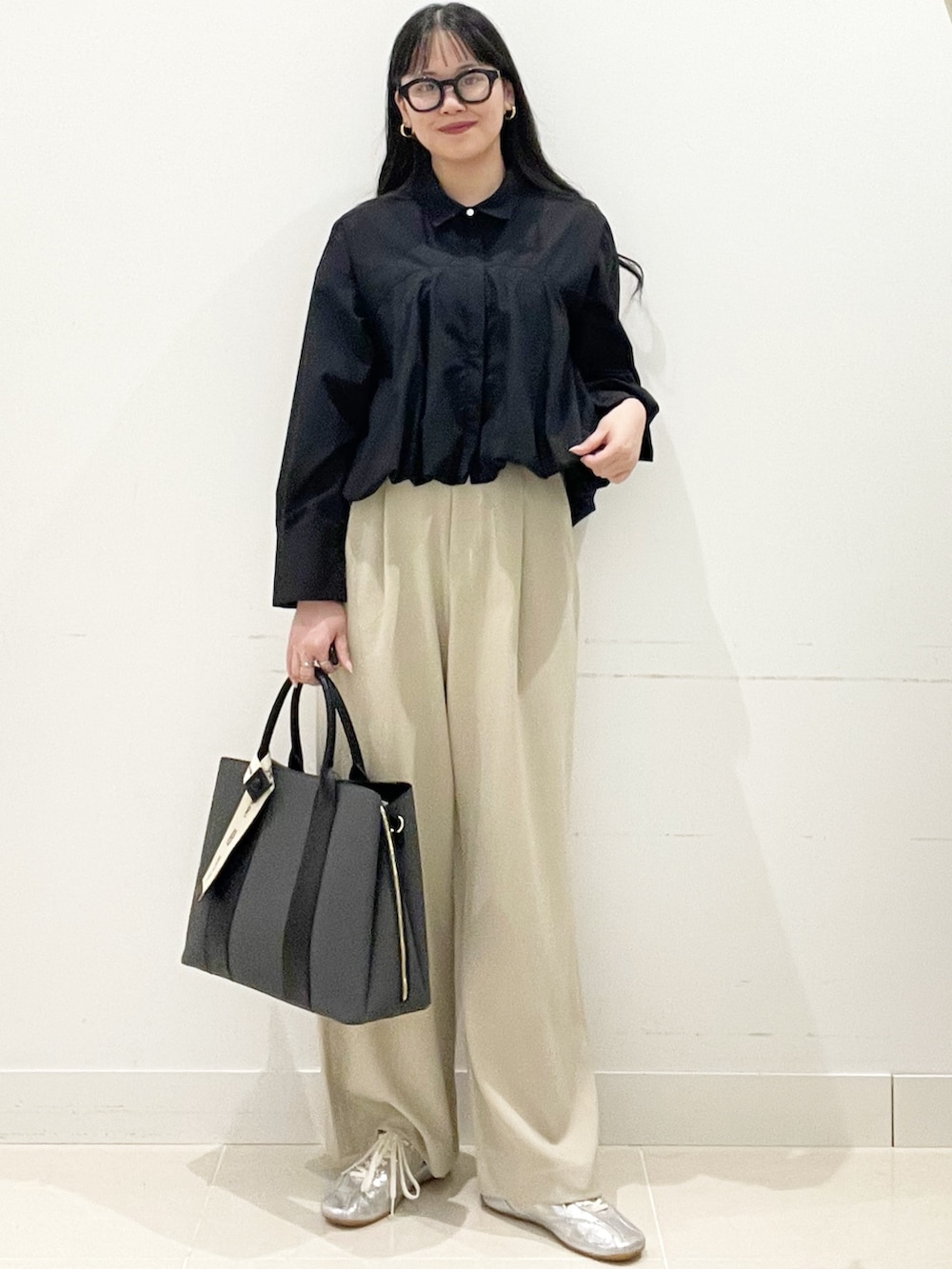 ベージュ系のスラックス、ブラック系のシャツ/ブラウス、ブラック系のトートバッグを着用したレディースの春コーディネートの2枚目の写真