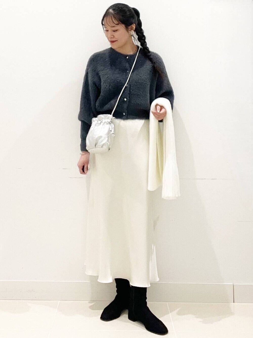 グレー系のニット/セーター、ブラック系のブーツ、シルバー系のショルダーバッグを着用したレディースの冬コーディネートの4枚目の写真