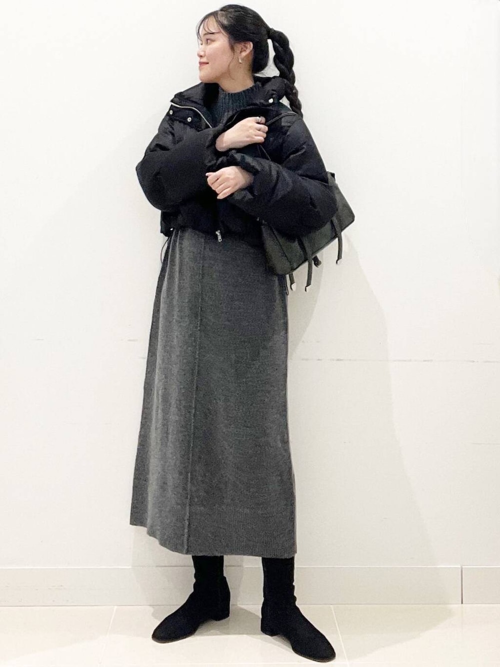 ブラック系のダウンジャケット/コート、ブラック系のブーツ、グレー系のワンピースを着用したレディースの冬コーディネートの3枚目の写真