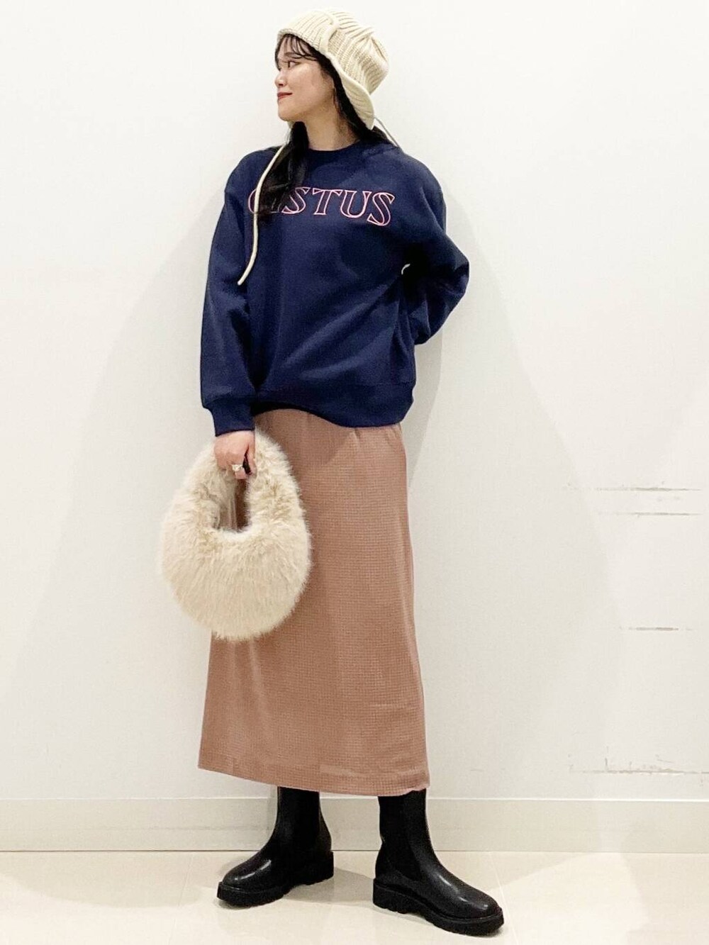 ベージュ系のハンドバッグ、ブラック系のブーツ、ピンク系のスカートを着用したレディースの秋コーディネートの2枚目の写真