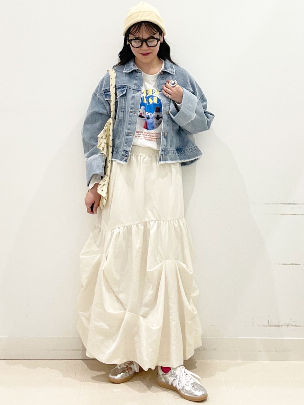 シルバー系のスニーカー、ホワイト系のスカート、ブルー系のデニムジャケットを着用したレディースの春コーディネートの3枚目の写真