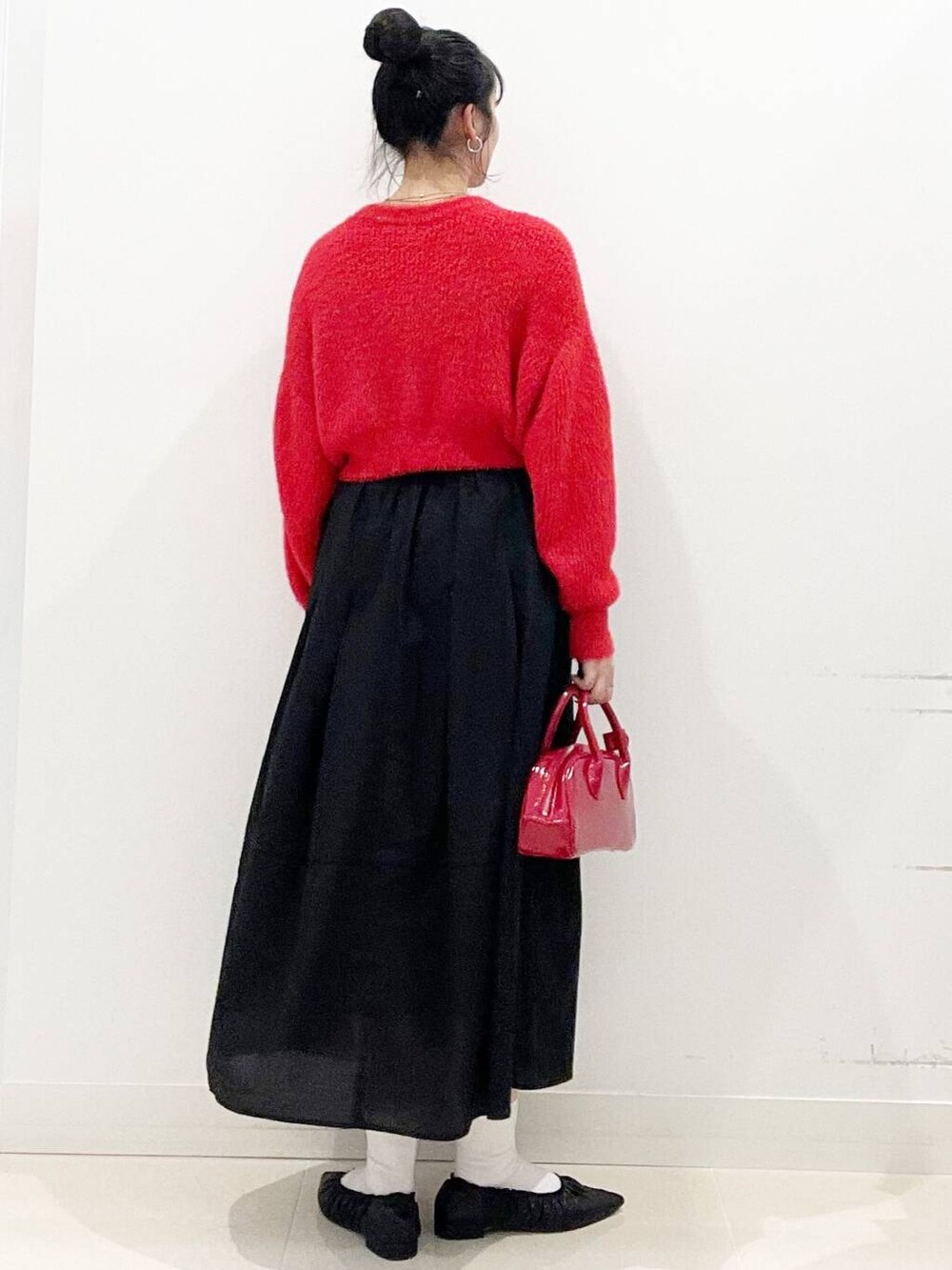 レッド系のボストンバッグ、レッド系のニット/セーター、ブラック系のバレエシューズを着用したレディースの冬コーディネートの7枚目の写真