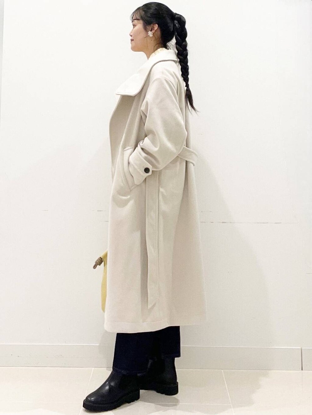 ブラック系のブーツ、ベージュ系のその他アウター、ブルー系のデニムパンツを着用したレディースの冬コーディネートの6枚目の写真