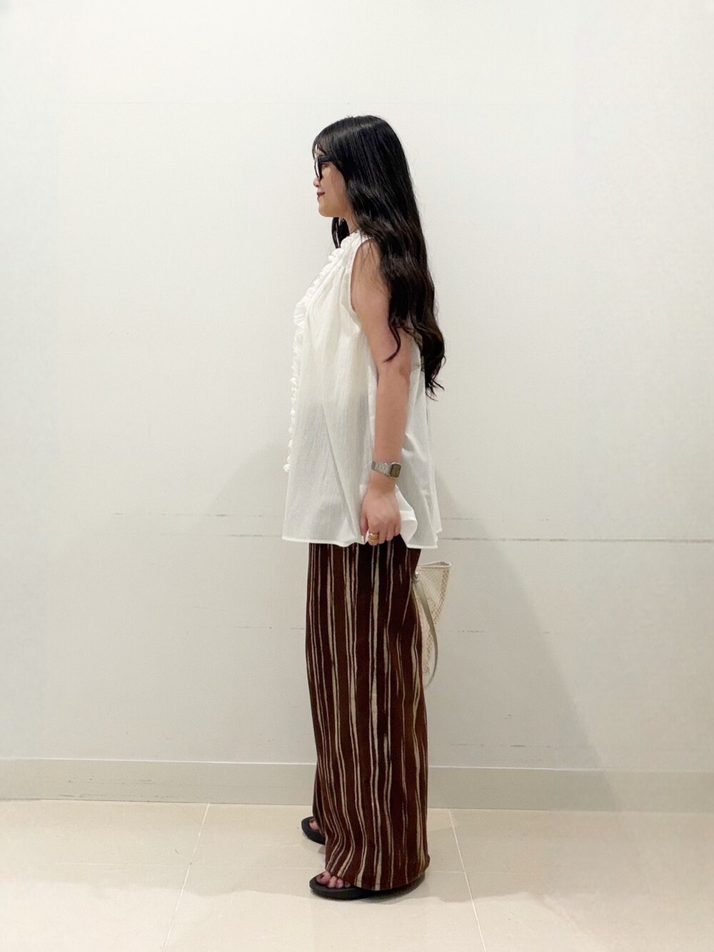 ブラウン系のデニムパンツ、ホワイト系のトートバッグ、ブラック系のサンダルを着用したレディースの夏コーディネートの4枚目の写真