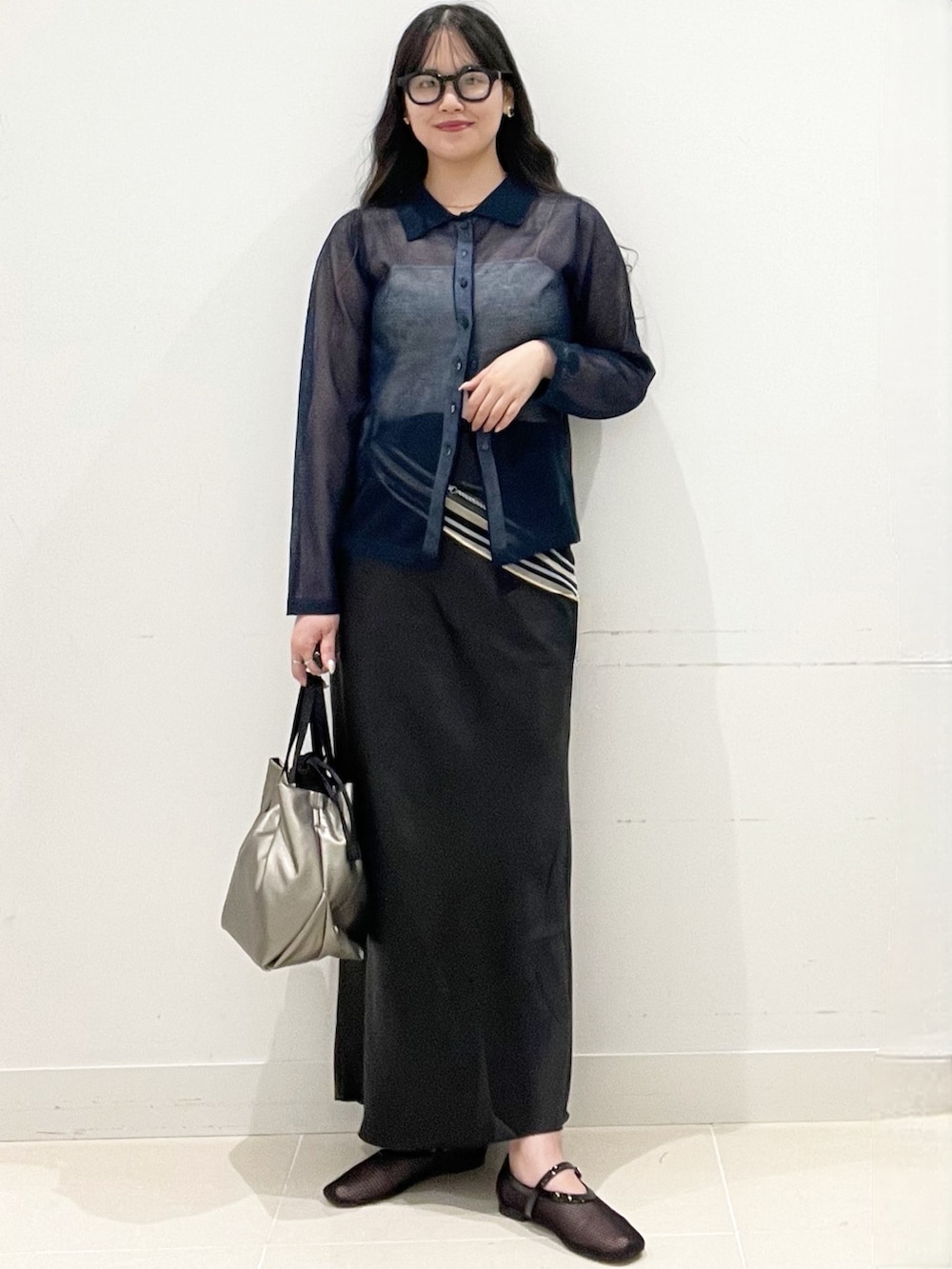 ブラック系のパンプス、ブラック系のスカート、シルバー系のショルダーバッグを着用したレディースの春コーディネートの3枚目の写真