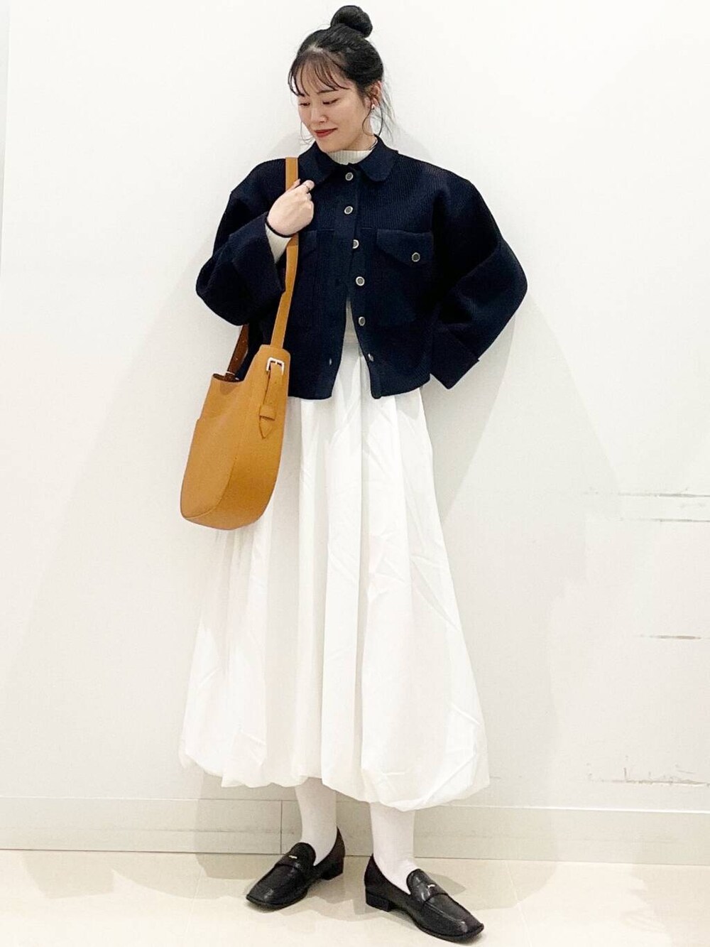 ホワイト系のスカート、ブラウン系のショルダーバッグ、ブラック系のローファーを着用したレディースの冬コーディネートの3枚目の写真