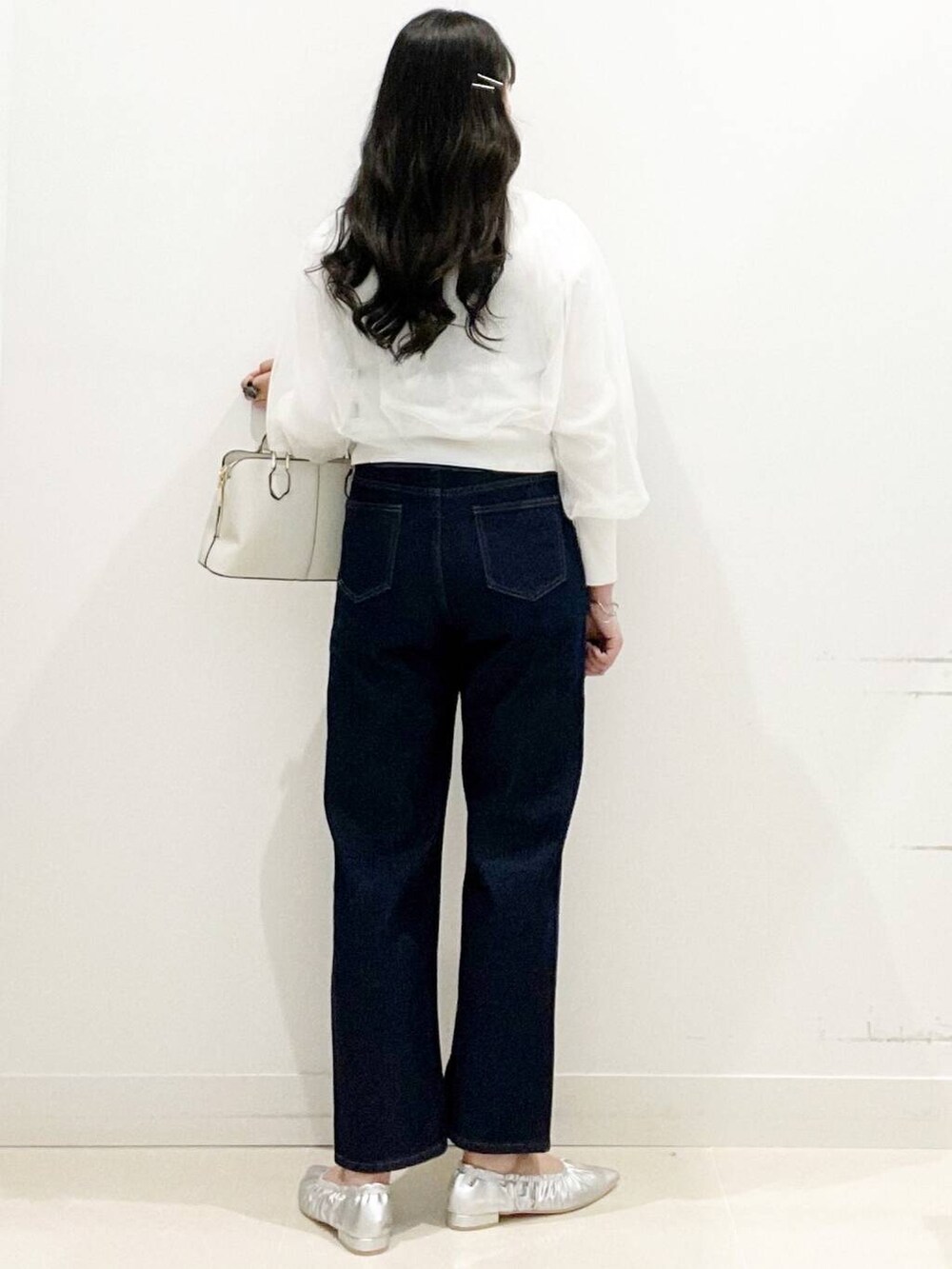 ブルー系のデニムパンツ、シルバー系のバレエシューズ、ホワイト系のカーディガン/ボレロを着用したレディースの春コーディネートの5枚目の写真