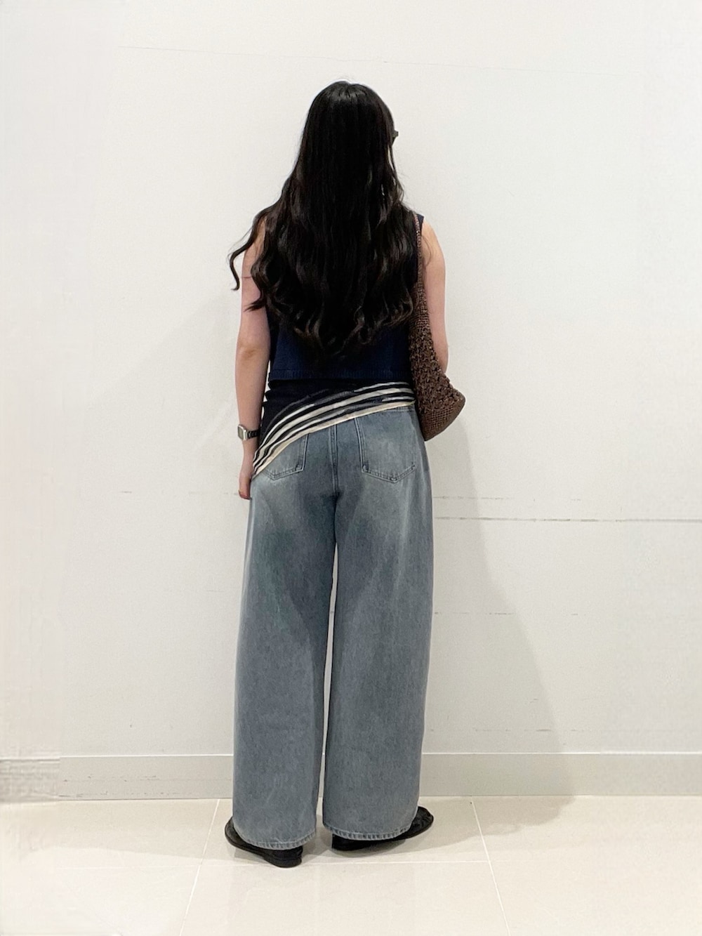 ブラック系のキャミソール、ブルー系のニット/セーター、ブルー系のデニムパンツを着用したレディースの春コーディネートの6枚目の写真