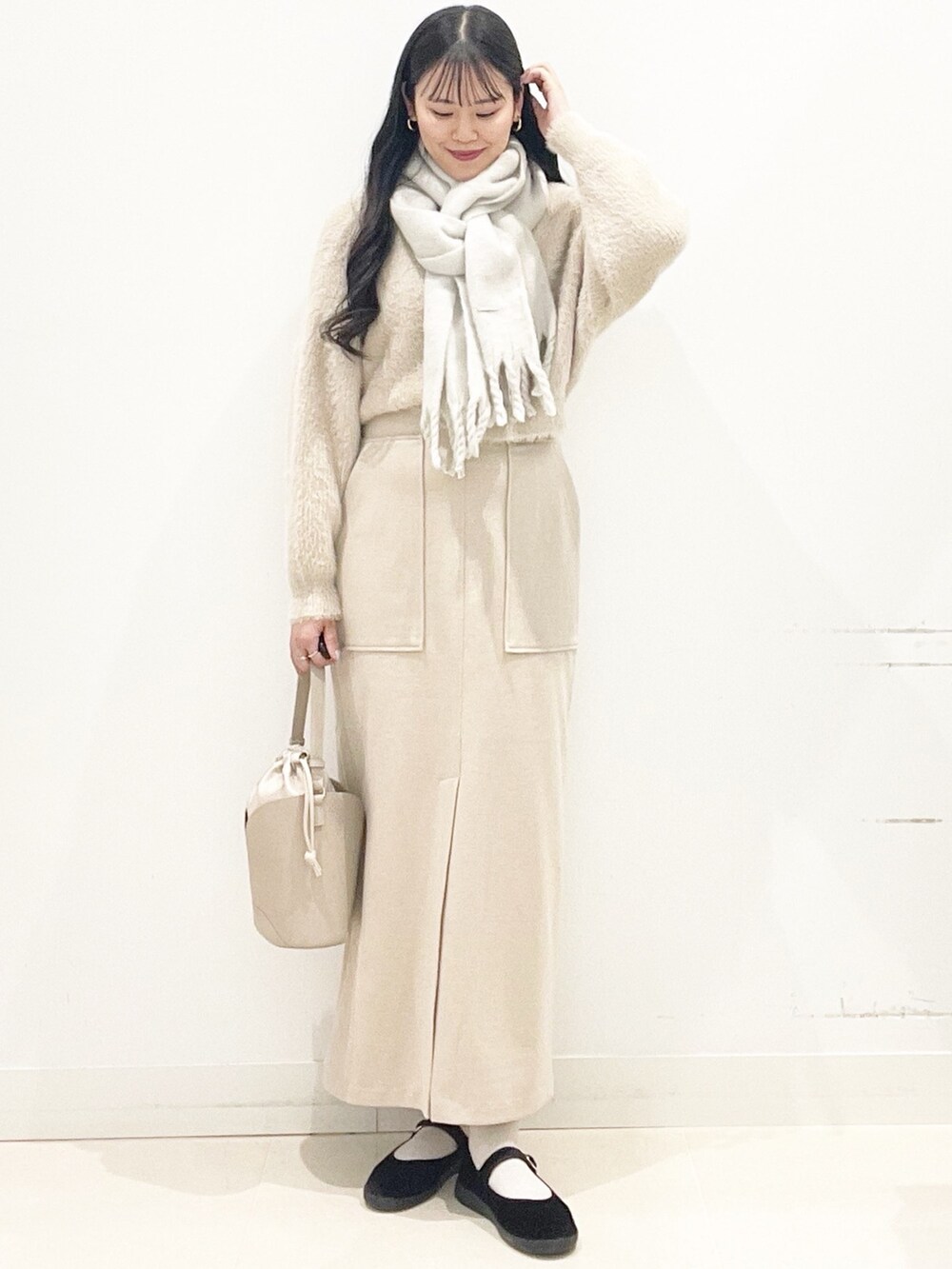 ブラック系のその他シューズ、ベージュ系のスカート、ベージュ系のハンドバッグを着用したレディースの秋コーディネートの5枚目の写真