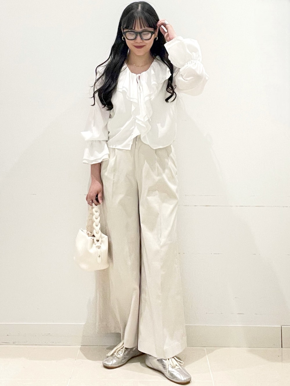 ホワイト系のチノパンツ、ホワイト系のショルダーバッグ、ホワイト系のキャミソールを着用したレディースの春コーディネートの2枚目の写真