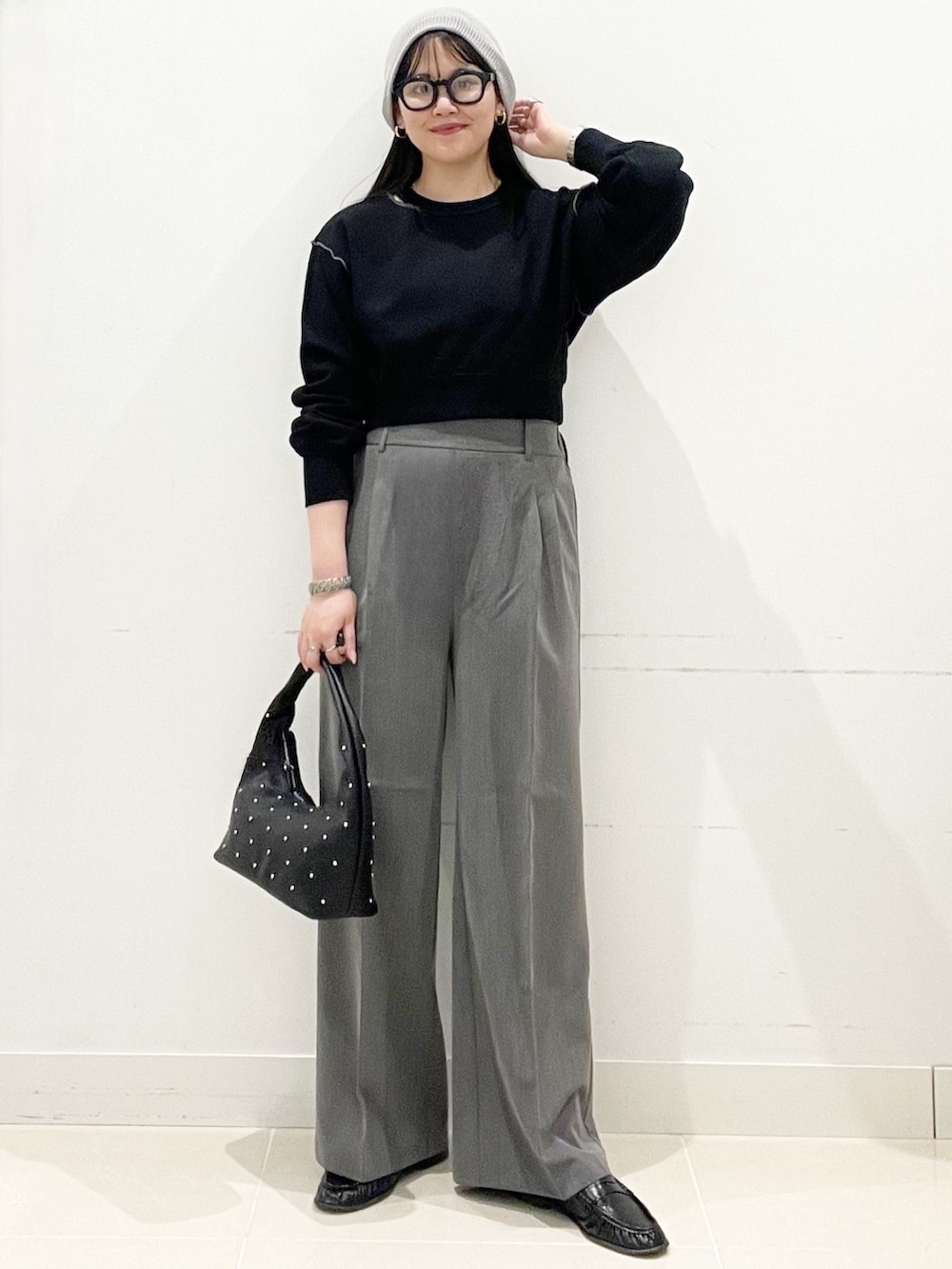 グレー系のスラックス、ブラック系のハンドバッグ、ブラック系のスウェットを着用したレディースの春コーディネートの2枚目の写真