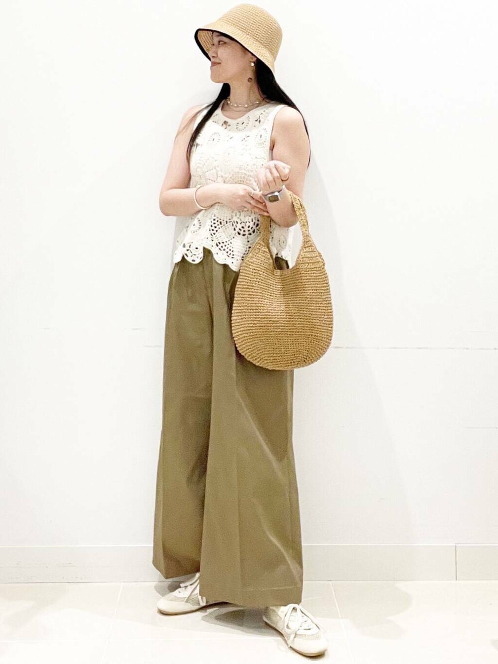 イエロー系のトートバッグ、ホワイト系のキャミソール、ホワイト系のベストを着用したレディースの夏コーディネートの2枚目の写真
