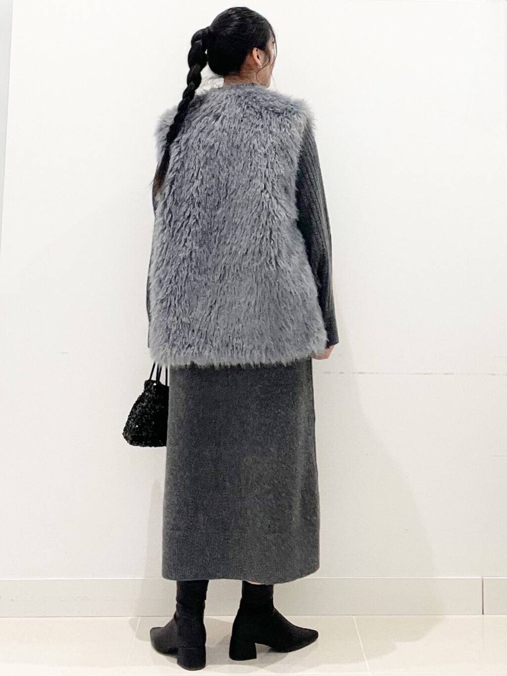 ブラック系のショルダーバッグ、グレー系のベスト、ブラック系のブーツを着用したレディースの冬コーディネートの6枚目の写真