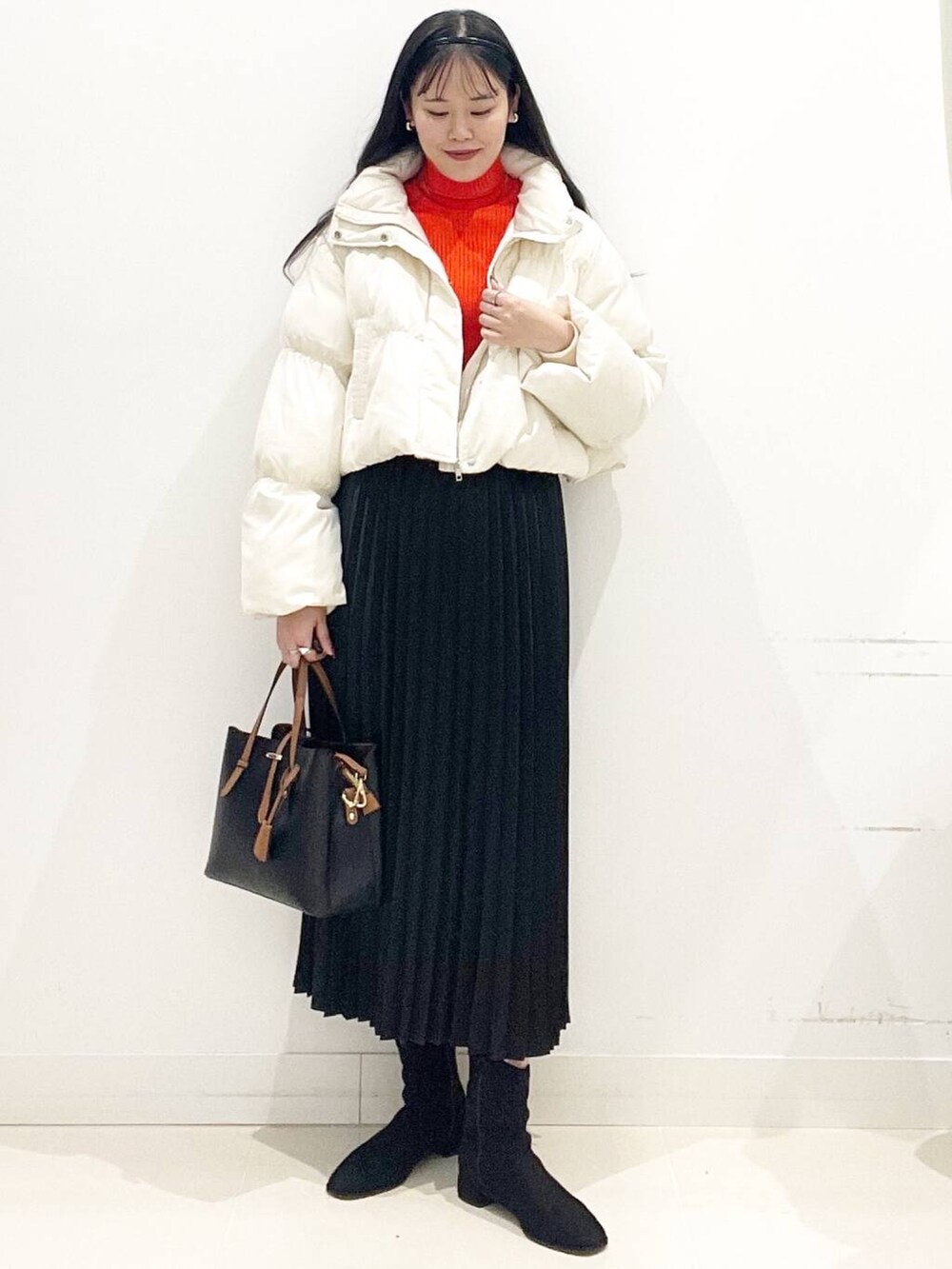 ブラック系のトートバッグ、ホワイト系のダウンジャケット/コート、ブラック系のブーツを着用したレディースの冬コーディネートの3枚目の写真