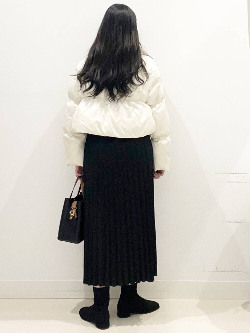 ブラック系のトートバッグ、ホワイト系のダウンジャケット/コート、ブラック系のブーツを着用したレディースの冬コーディネートの5枚目の写真