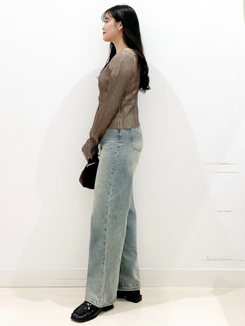 ブラウン系のハンドバッグ、ブラック系のローファー、ブラウン系のニット/セーターを着用したレディースの秋コーディネートの5枚目の写真