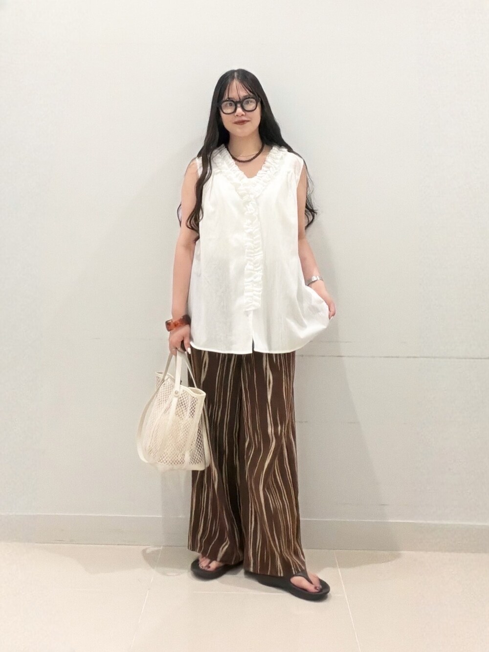 ブラウン系のデニムパンツ、ホワイト系のトートバッグ、ブラック系のサンダルを着用したレディースの夏コーディネートの2枚目の写真