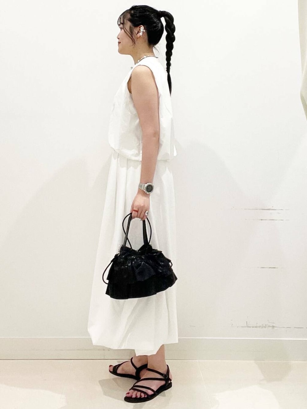 ブラック系のショルダーバッグ、ホワイト系のスカート、ホワイト系のキャミソールを着用したレディースの夏コーディネートの5枚目の写真