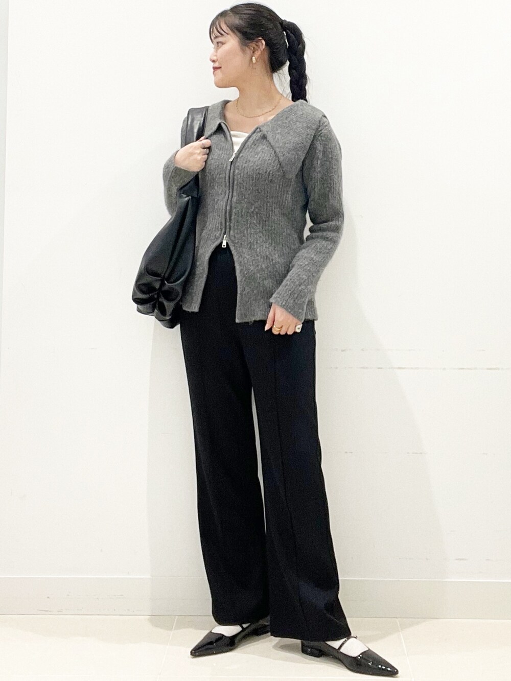 グレー系のカーディガン/ボレロ、ブラック系のパンプス、ホワイト系のTシャツ/カットソーを着用したレディースの冬コーディネートの2枚目の写真