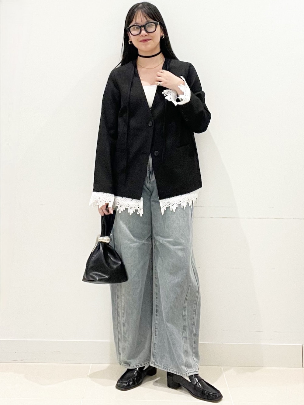 ブラック系のローファー、ブルー系のデニムパンツ、ブラック系のハンドバッグを着用したレディースの春コーディネートの3枚目の写真