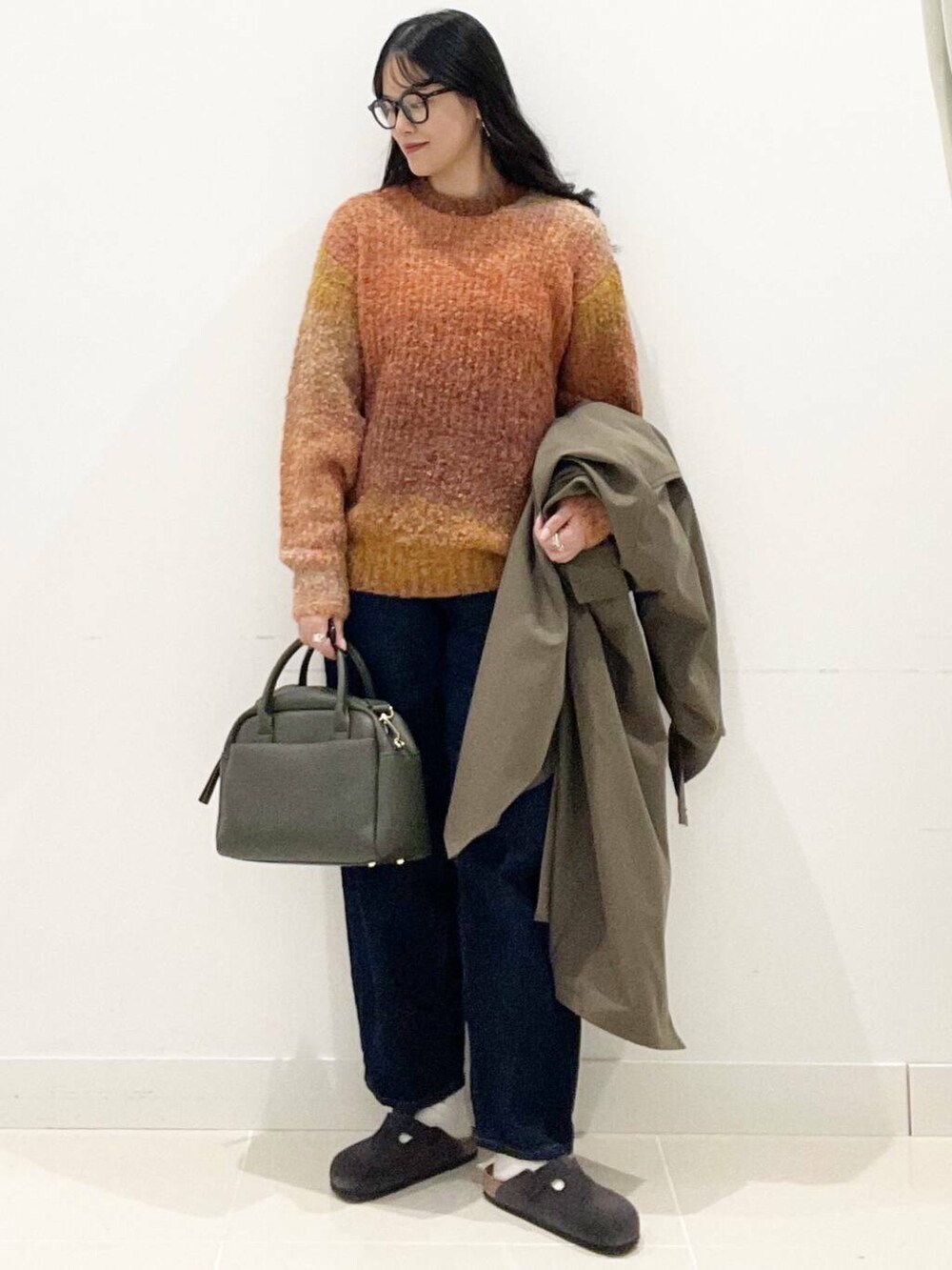 グリーン系のボストンバッグ、ブルー系のデニムパンツ、ブラウン系のその他アウターを着用したレディースの秋コーディネートの2枚目の写真