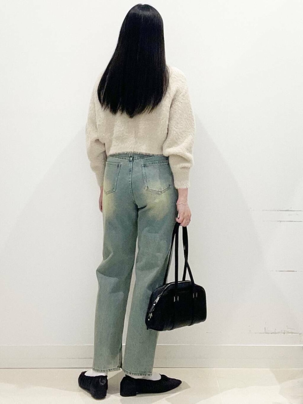 ベージュ系のニット/セーター、ブラック系のボストンバッグ、ブルー系のデニムパンツを着用したレディースの冬コーディネートの6枚目の写真