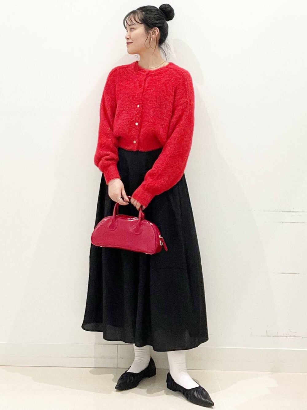 レッド系のボストンバッグ、レッド系のニット/セーター、ブラック系のバレエシューズを着用したレディースの冬コーディネートの3枚目の写真