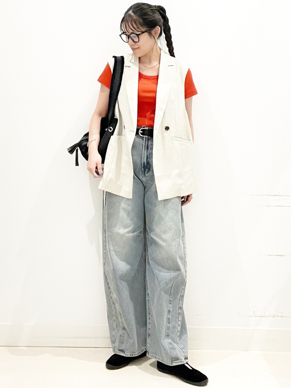 ベージュ系のベスト、レッド系のTシャツ/カットソー、ブルー系のデニムパンツを着用したレディースの夏コーディネートの3枚目の写真