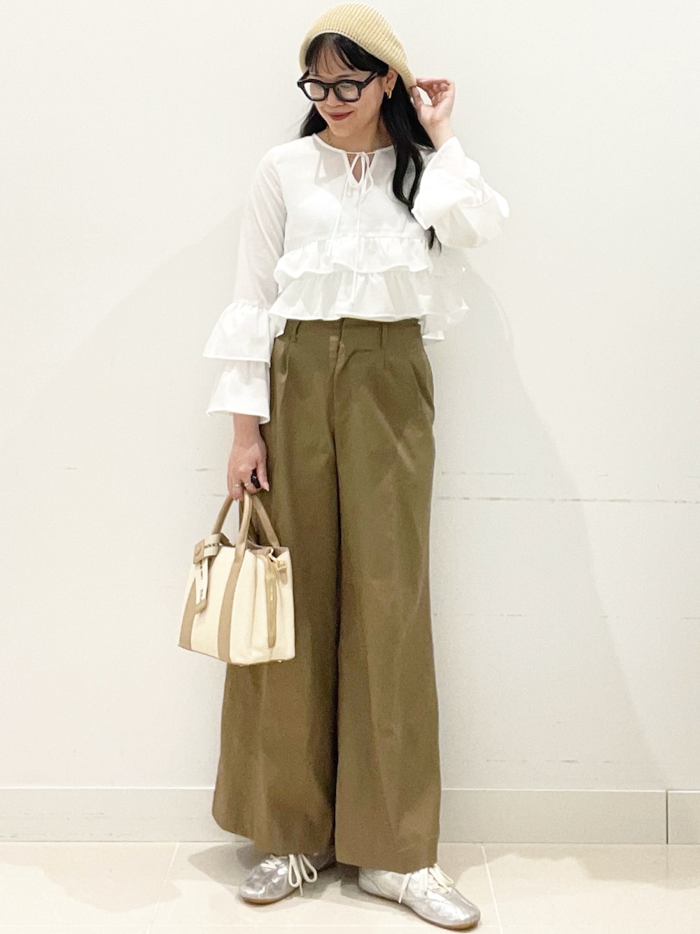 ベージュ系のチノパンツ、ホワイト系のハンドバッグ、ホワイト系のキャミソールを着用したレディースの春コーディネートの3枚目の写真