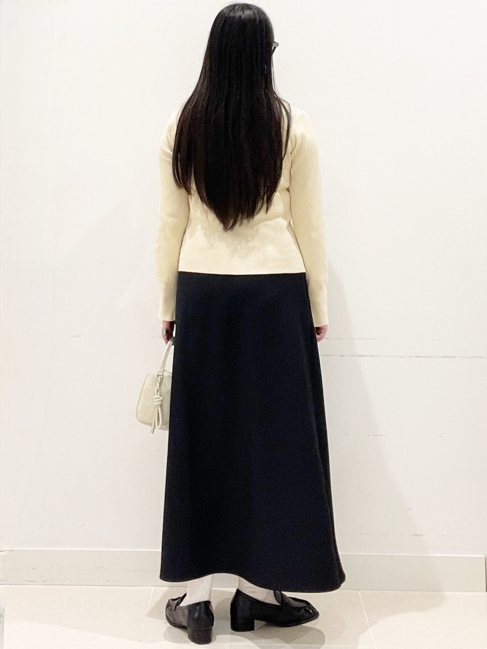 ブラック系のローファー、ブラック系のスカート、ベージュ系のハンドバッグを着用したレディースの春コーディネートの4枚目の写真