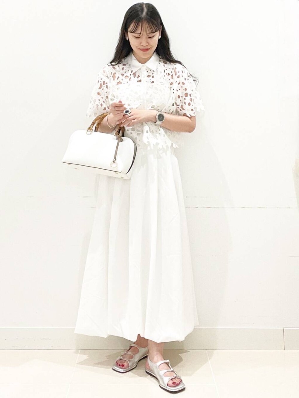 ホワイト系のスカート、ホワイト系のキャミソール、ホワイト系のハンドバッグを着用したレディースの夏コーディネートの4枚目の写真