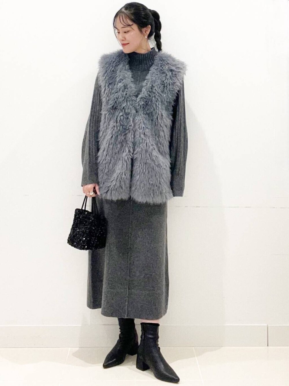 ブラック系のショルダーバッグ、グレー系のベスト、ブラック系のブーツを着用したレディースの冬コーディネートの4枚目の写真