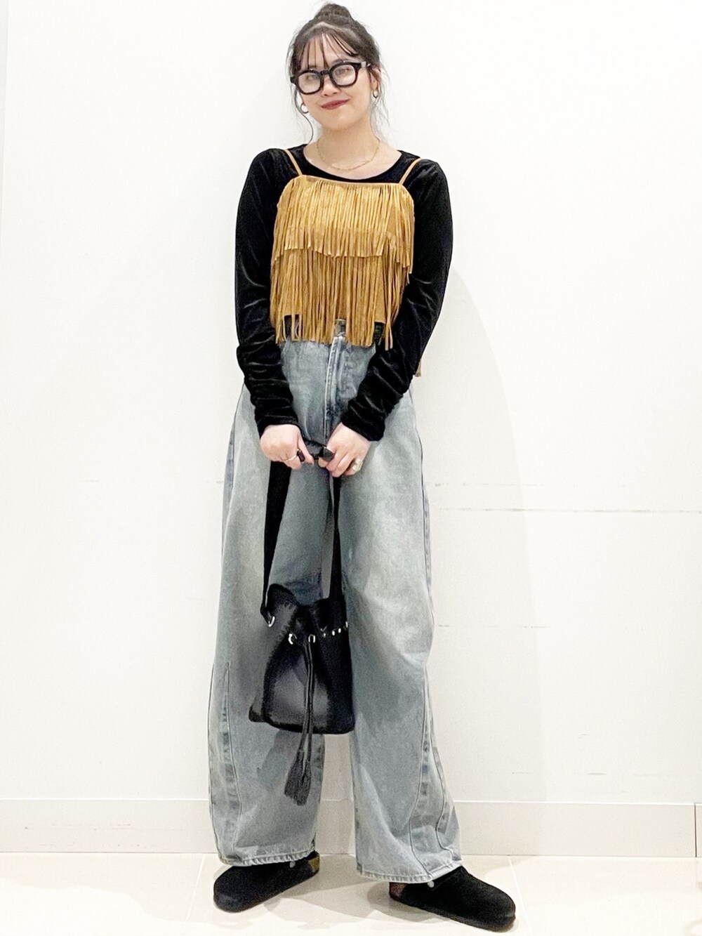 ブラック系のサンダル、ブラック系のショルダーバッグ、ブルー系のデニムパンツを着用したレディースの秋コーディネートの2枚目の写真