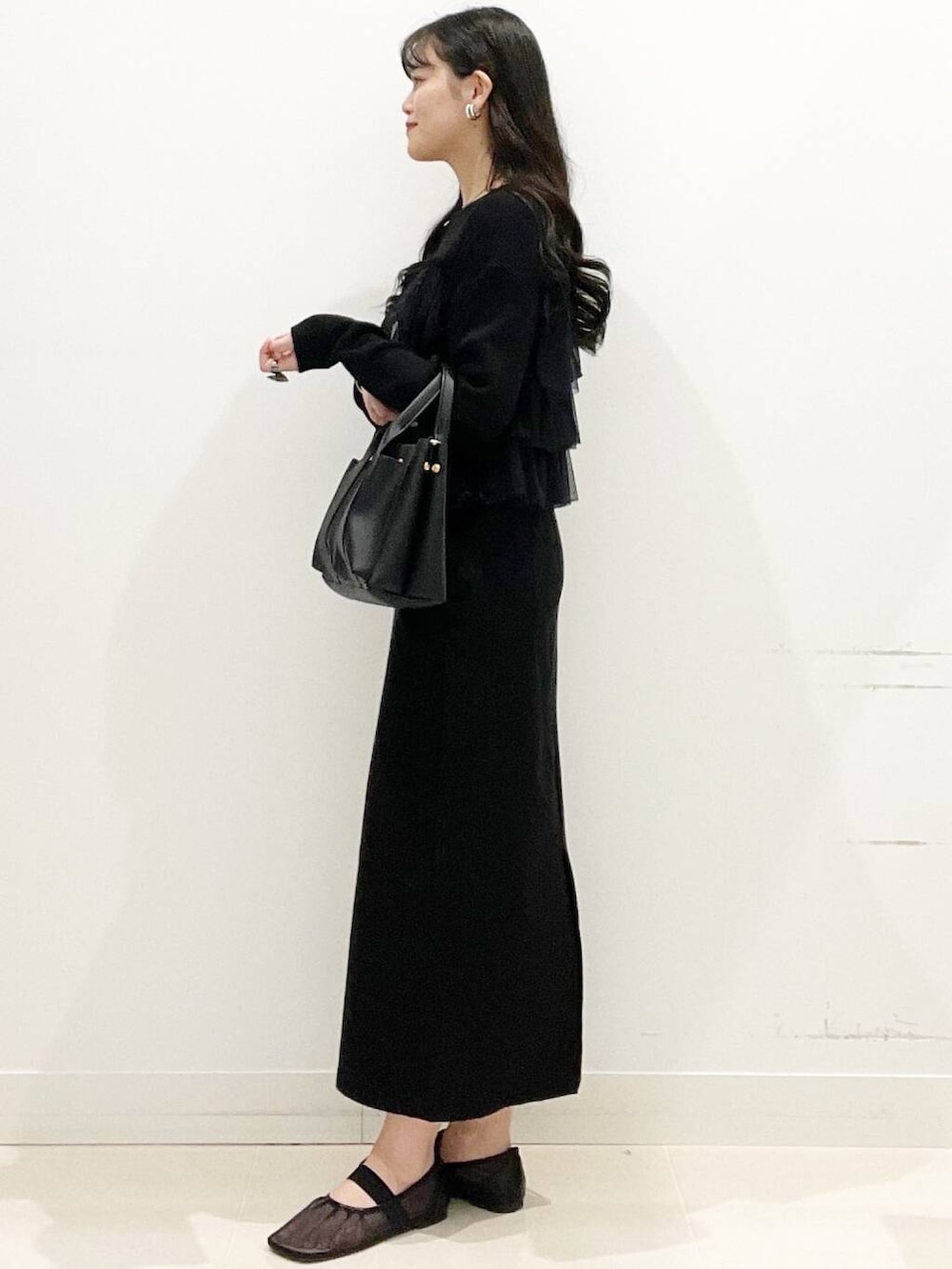 ブラック系のニット/セーター、ブラック系のスカート、ブラック系のトートバッグを着用したレディースの春コーディネートの4枚目の写真