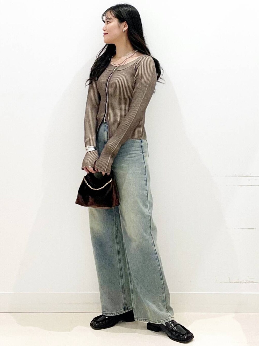 ブラウン系のハンドバッグ、ブラック系のローファー、ブラウン系のニット/セーターを着用したレディースの秋コーディネートの3枚目の写真