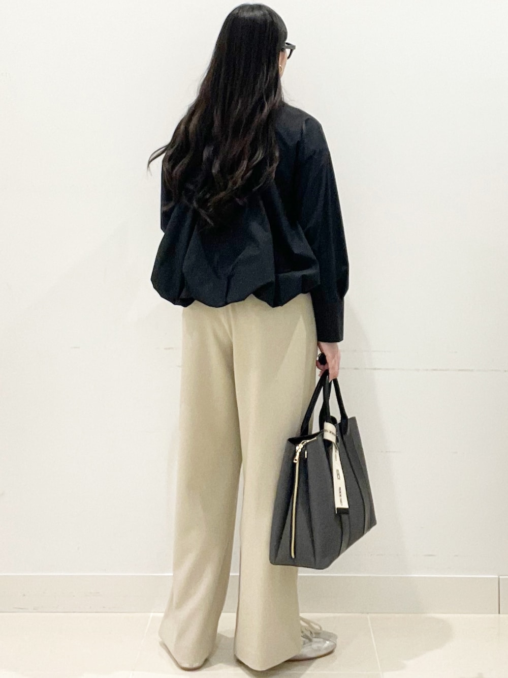 ベージュ系のスラックス、ブラック系のシャツ/ブラウス、ブラック系のトートバッグを着用したレディースの春コーディネートの4枚目の写真