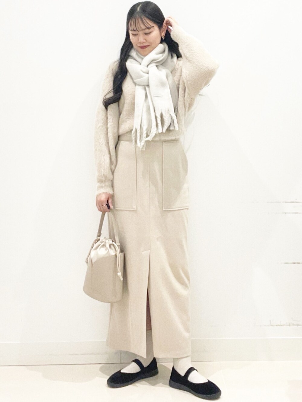 ブラック系のその他シューズ、ベージュ系のスカート、ベージュ系のハンドバッグを着用したレディースの秋コーディネートの4枚目の写真