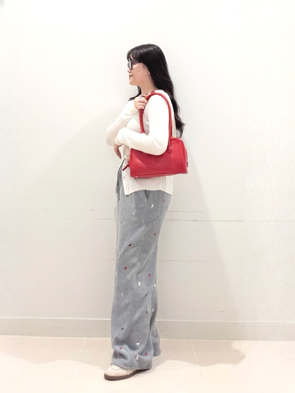 ホワイト系のニット/セーター、グレー系のその他パンツ、レッド系のボストンバッグを着用したレディースの秋コーディネートの4枚目の写真