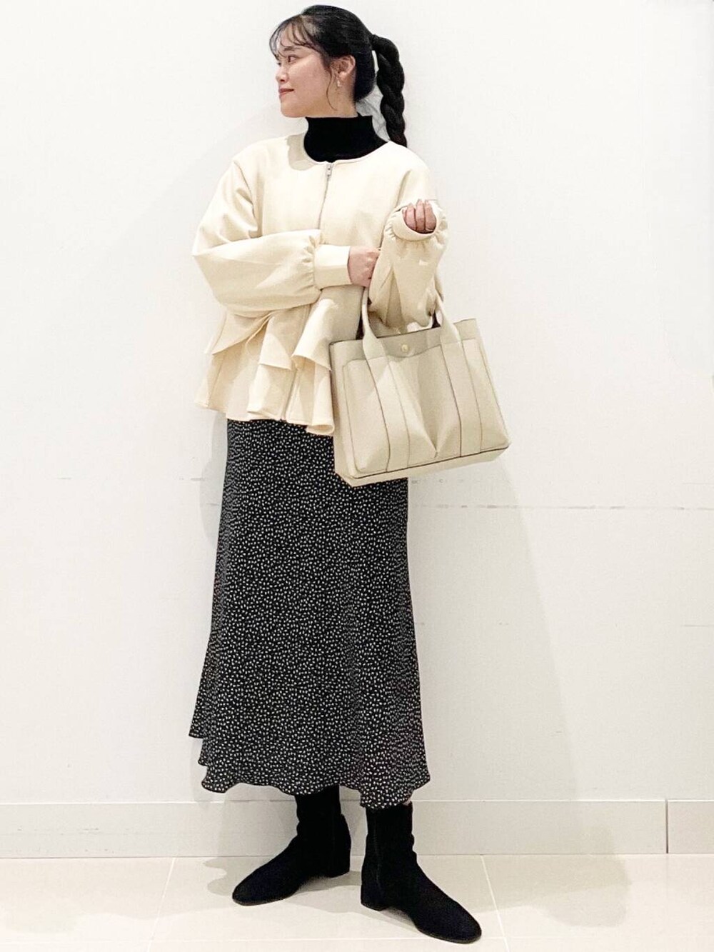 ブラック系のニット/セーター、ブラック系のブーツ、ホワイト系のトートバッグを着用したレディースの冬コーディネートの2枚目の写真