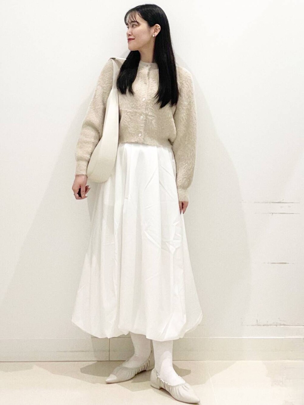 ホワイト系のスカート、ベージュ系のニット/セーター、ホワイト系のショルダーバッグを着用したレディースの冬コーディネートの2枚目の写真
