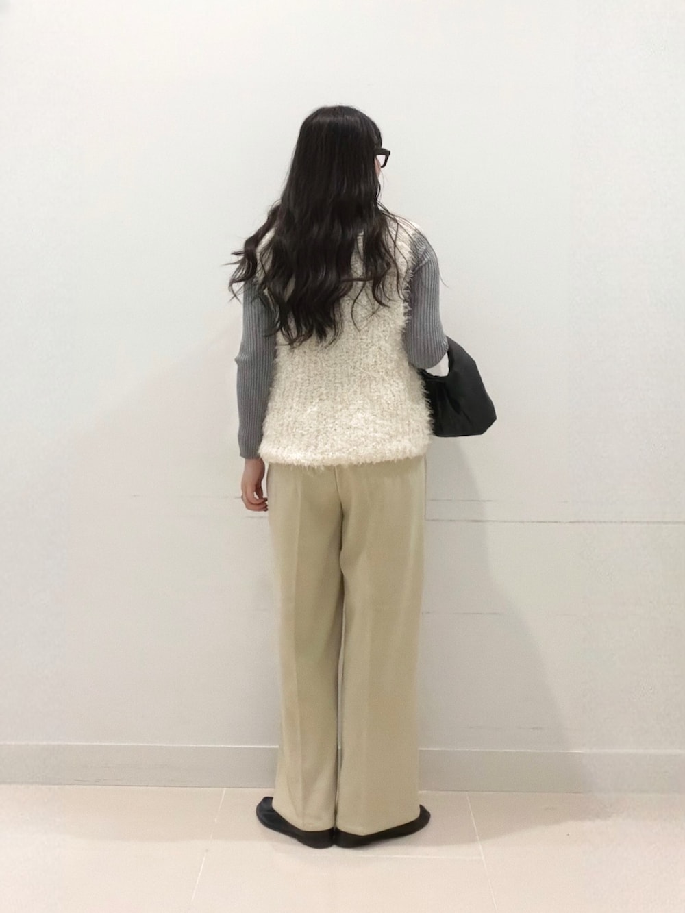 グレー系のニット/セーター、ベージュ系のその他パンツ、ホワイト系のベストを着用したレディースの秋コーディネートの4枚目の写真