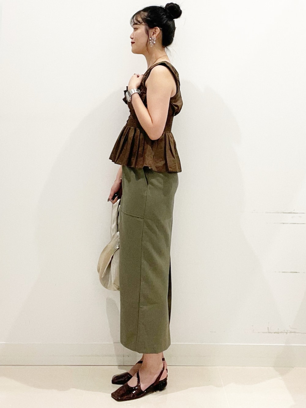 グリーン系のスカート、ブラック系のキャミソール、ゴールド系のハンドバッグを着用したレディースの夏コーディネートの6枚目の写真