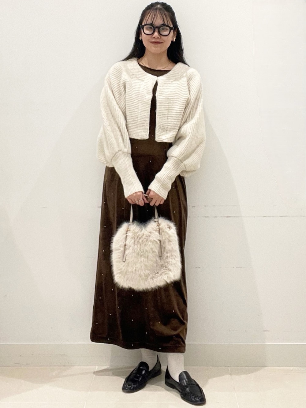 ホワイト系のショルダーバッグ、ブラウン系のワンピース、ベージュ系のニット/セーターを着用したレディースの冬コーディネートの2枚目の写真