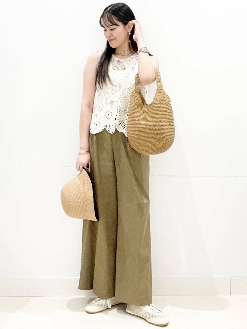 イエロー系のトートバッグ、ホワイト系のキャミソール、ホワイト系のベストを着用したレディースの夏コーディネートの3枚目の写真