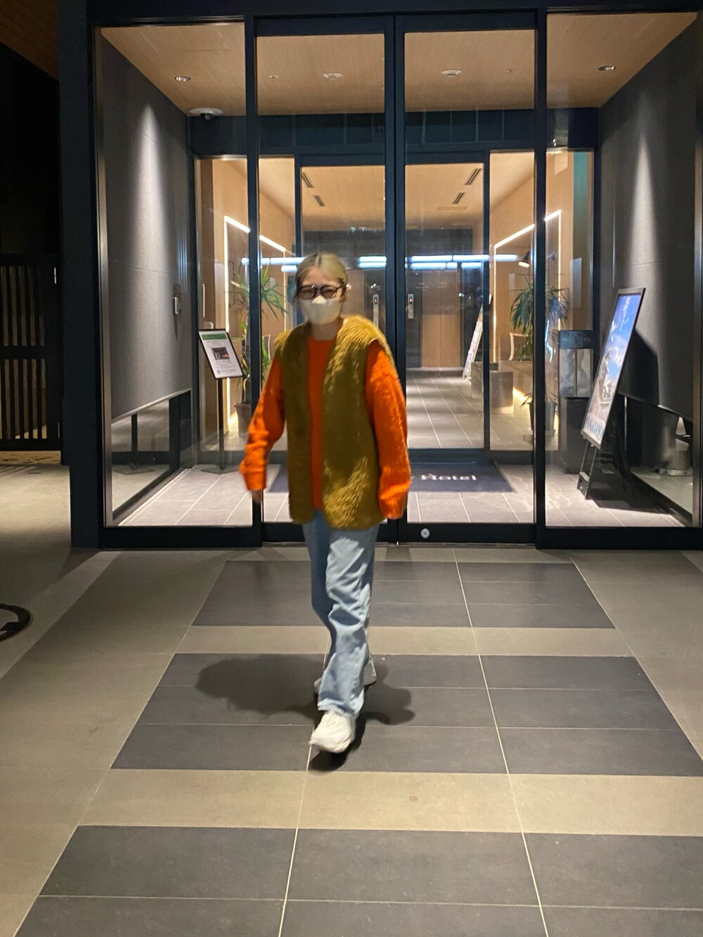 ブルー系のパンツ、ホワイト系のスニーカー、オレンジ系のトップスを着用したレディースの冬コーディネートの2枚目の写真